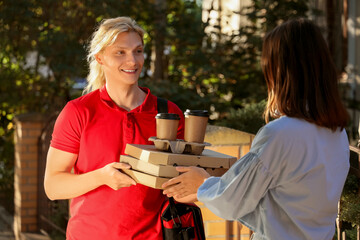 Male courier delivering pizza with coffee to woman outdoors