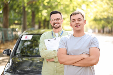 Obraz premium Smiling young man with driving instructor on street