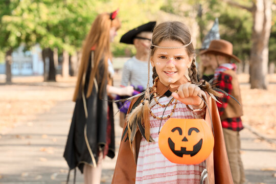 Little girl dressed for Halloween with her friends in park