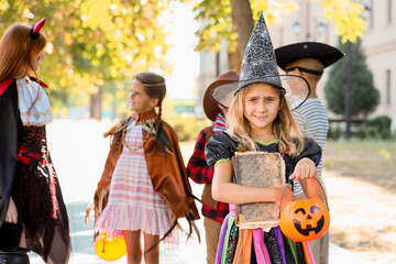Little girl dressed for Halloween with her friends on street