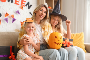 Cute girls with gifts and their grandmother celebrating Halloween at home