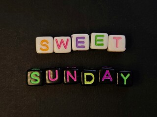 Colorful Sweet Sunday Message with Letter Beads on Dark Background.