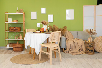 Interior of stylish dining room with table, sofa and autumn decor