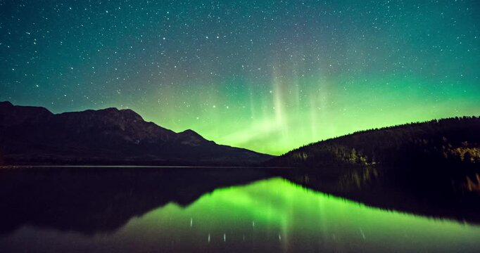 Time lapse of Aurora, northern lights glowing over pine forest at Pyramid Lake located at the foot of Pyramid Mountain in Jasper National Park, Alberta, Canada.