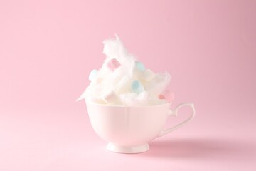 Tasty cotton candy with colorful marshmallows in cup on pink background, closeup