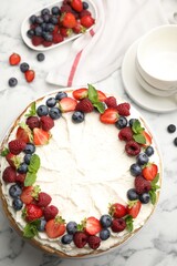 Delicious crepe cake with fresh berries on white marble table, flat lay