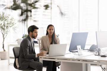 Two young multiethnic coworkers meeting at laptop