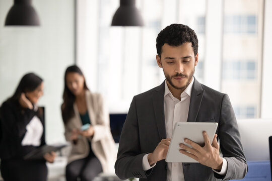 Busy young Middle Eastern business professional man typing on tablet