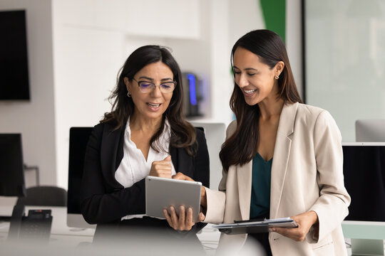 Happy diverse coworkers using web service on digital tablet