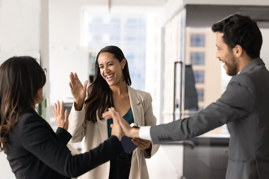 Excited happy diverse employees giving high five to elder boss