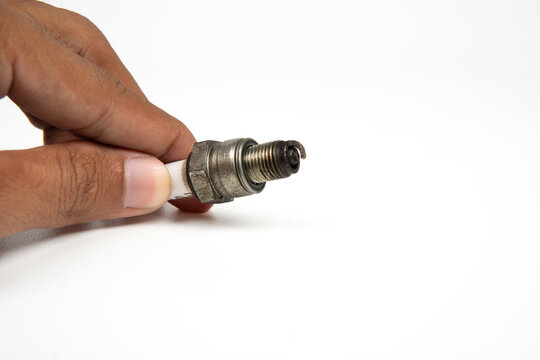 Used spark plug on white background, close-up detail of automotive engine part isolated for repair and maintenance concept.