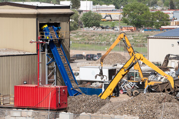 Machines sorting scrap metal at a recycling plant with conveyer belts in an industrial park.
