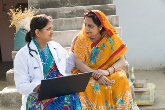Indian female doctor medical discussing to rural female patient in village. Concept of Woman Health Problems in rural sectors. female doctor using laptop in rural camp.