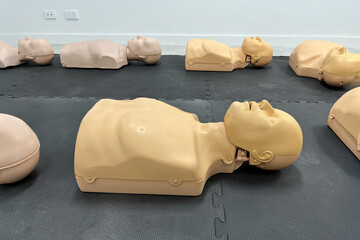 CPR training mannequins on a black mat in a classroom setting.