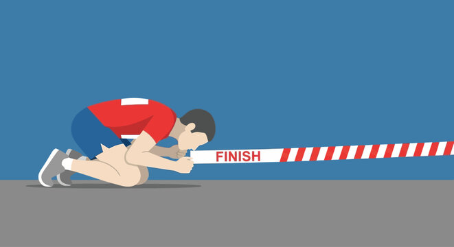 A determined athlete lunges forward, head bowed, pushing through the finish line tape in a moment of intense athletic exertion.