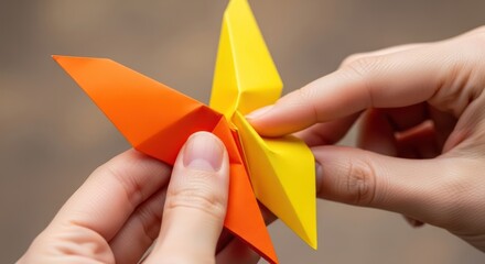 Naklejka premium Close-up of hands folding a colorful origami star, showcasing the intricate papercraft process.