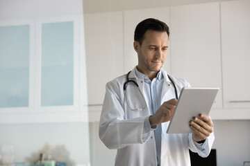 Focused mid aged physician using ai tool on digital tablet