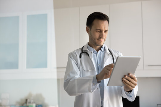 Focused mid aged physician using ai tool on digital tablet