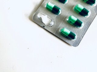 green capsules in a blister on a white background, with one capsule was already taken