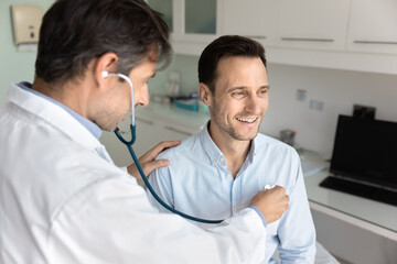 Smiling mid aged male patient visit doctor for heart examination