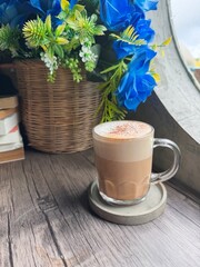 Warm Coffee Mug on Wooden Table with Blue Flowers and Books