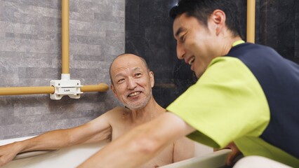 入浴介助を受けるアジア人高齢者 © mapo