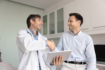 Friendly doctor holding tablet shaking hands with male pharma representative