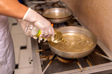 Chef adding cooking oil to frying pan