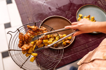 Woman serving fried chicken wings and potatoes