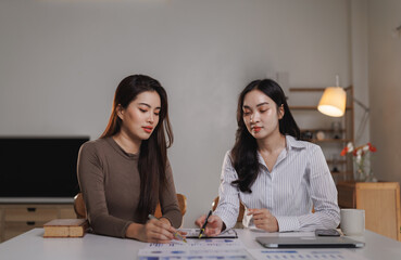 Fototapeta premium Two businesswomen working together analyzing charts and graphs at home office