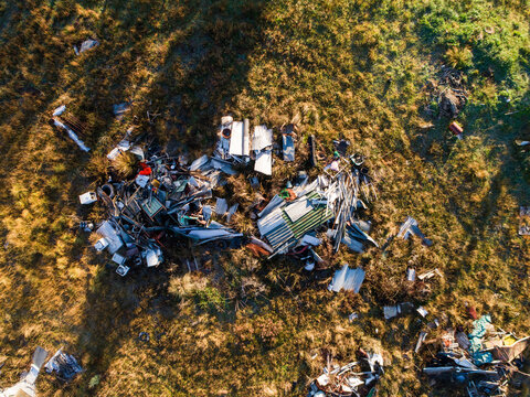 Aerial overhead view of piled of junk and old metal in grassy farm paddock
