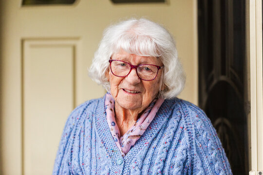 Portrait of happy 99 year old elderly Australian woman standing by front door of her home