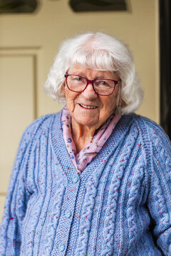 Portrait of happy 99 year old elderly Australian woman standing by front door of her home