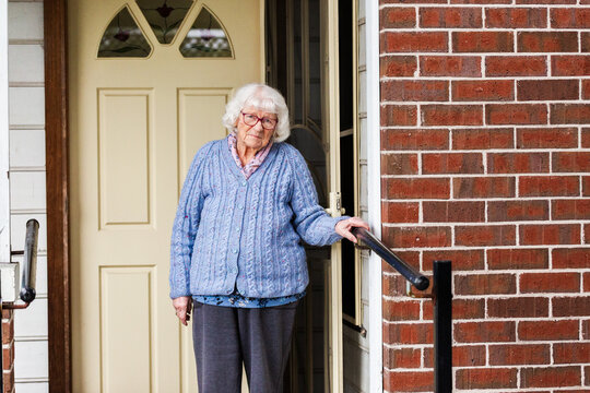 Portrait of 99 year old elderly Australian woman standing by front door of her home