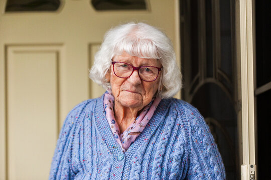 Portrait of 99 year old elderly Australian woman standing by front door of her home