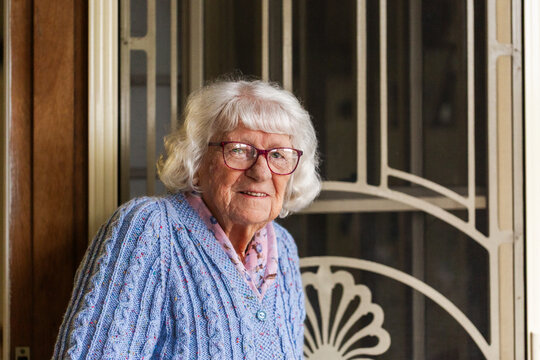 Portrait of 99 year old elderly Australian woman standing by front door of her home