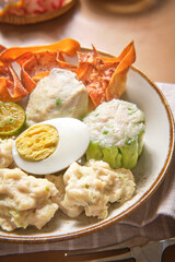 Plate of siomay with side dishes suitable for food blogs, restaurant menus, asian cuisine articles, indonesian cuisine promotions, cooking magazines.
