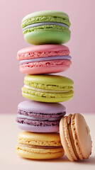 Colorful stack of pastel macarons balanced against pastel background. 
