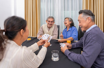 cheerful senior friends enjoy playing cards game together at home,concept elderly people activity, entertainment,recreation,encourages social interaction,help memory retention