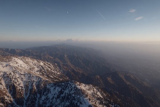 High-angle view of snow-capped mountain range at sunset. Vast landscape stretches out