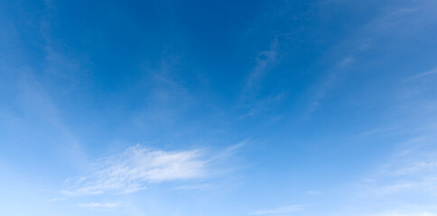 A bright blue morning sky with a few clouds and sunlight for nature background.