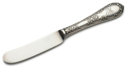 An ornate antique silver butter knife with floral engravings and a monogrammed handle.