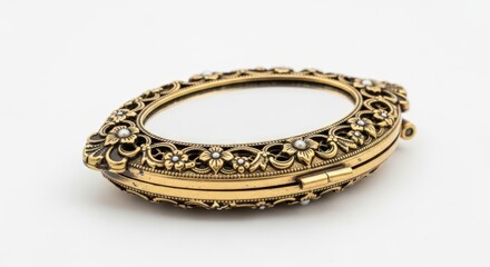 An antique oval-shaped golden compact mirror with intricate floral engravings and small pearl accents, set against a white background.