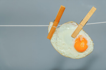 Clothespins holding a fried egg on a clothesline, representing a creative food concept