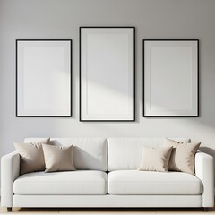Three framed art pieces hang above a white couch with beige throw pillows in a bright, minimalist living room.