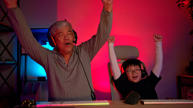 Happy grandfather playing games with grandchild in in a neon lit room - Powered by Adobe
