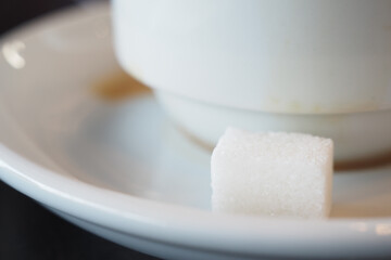 Warm coffee with sugar cube on white saucer