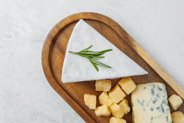 Selection of assorted cheeses served on a wooden platter with herbs