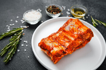 Marinated pork ribs on white plate with herbs and spices
