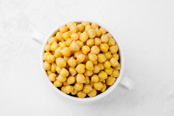 Cooked chickpeas in white bowl on textured dark background for plantbased food, healthy lifestyle or vegan meal concept